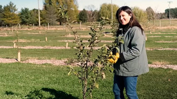 A woman next to a fruit tree.