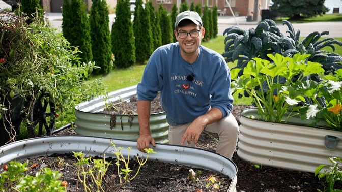 A man kneeling by a raised garden bed.