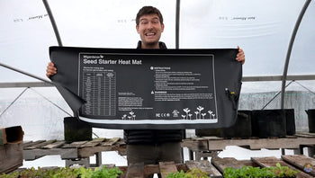 A man holding a jumbo seedling heat mat.