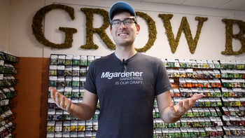 A man standing in front of racks full of seeds for sale.
