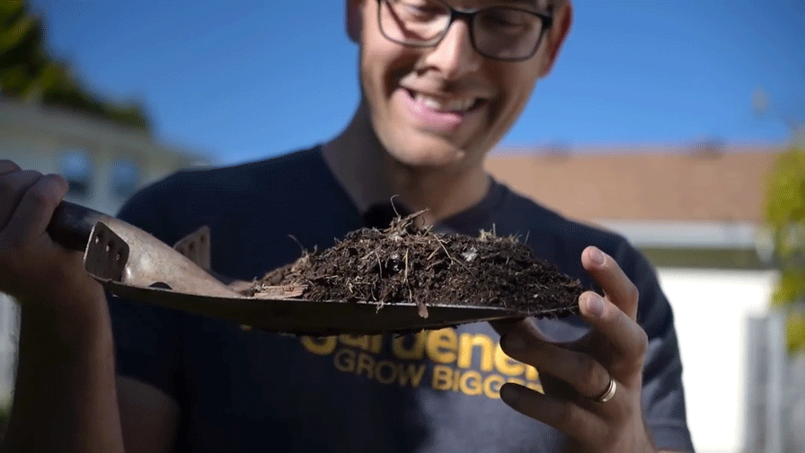 A man holding a shovelful of compost.