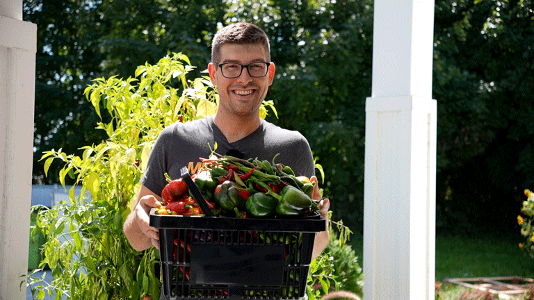 A man holding a bin of peppers.
