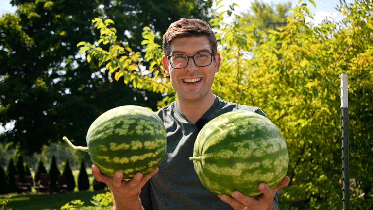 A man holding two watermelons.